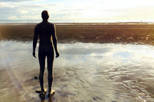 Help with loneliness - one of Antony Gormley's 'iron men' sculptures on Crosby beach looking out to sea. The tide is out.