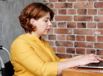 Woman in wheelchair at work on laptop - The benefits of hiring a more neurodiverse workforce are huge.