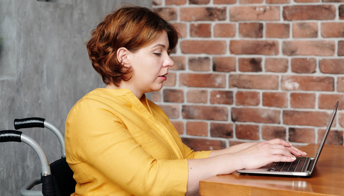 Woman in wheelchair at work on laptop - The benefits of hiring a more neurodiverse workforce are huge.