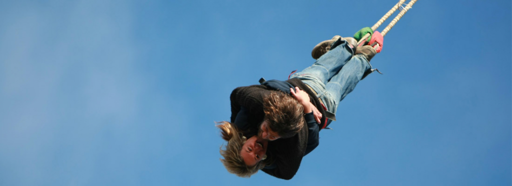 Two people hang upside down during a bungee jump