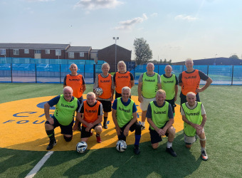 Everton in the Community's Walking Football Parkinson's team kneel on the pitch