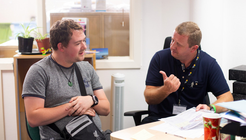 A member of Brain Charity staff speaks to a man at our centre