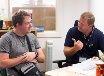 A member of Brain Charity staff speaks to a man at our centre