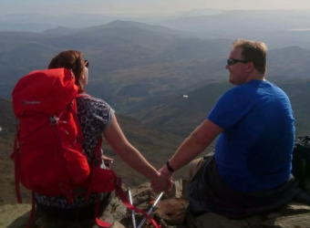 Erin sitting on a hillside enjoying view and holding hands with her husband James