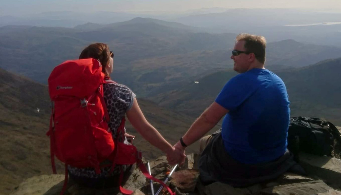 Erin sitting on a hillside enjoying view and holding hands with her husband James