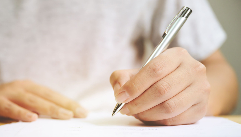 Close up of hand holding a pen and signing a document