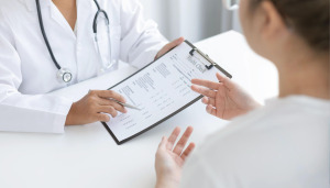 Doctor holding a clipboard with a health survey and showing it to a patient