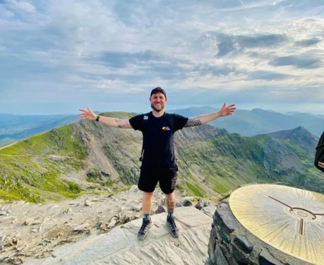 A fundraiser in a Brain Charity t-shirt at the summit of one of the UK's Three Peaks.