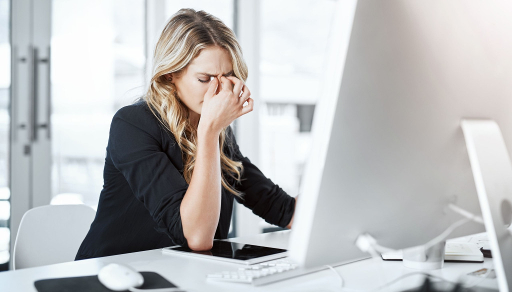 Woman sitting at a desk while experiencing a headache