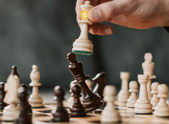 A hand moving a piece to win a game on a chess board