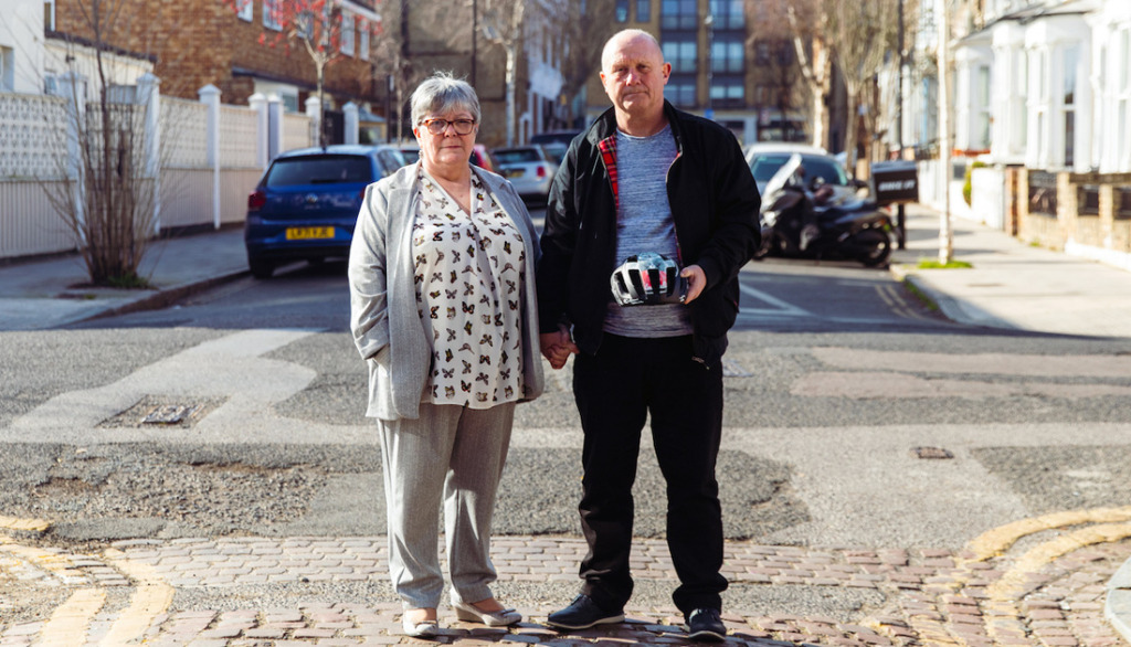 Ian with his wife holding an Endura cycling helmet with a design based on his CAT scan