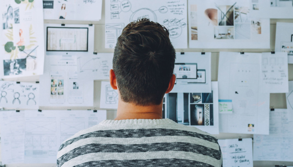 Man making connections between different pieces of information on a pin board