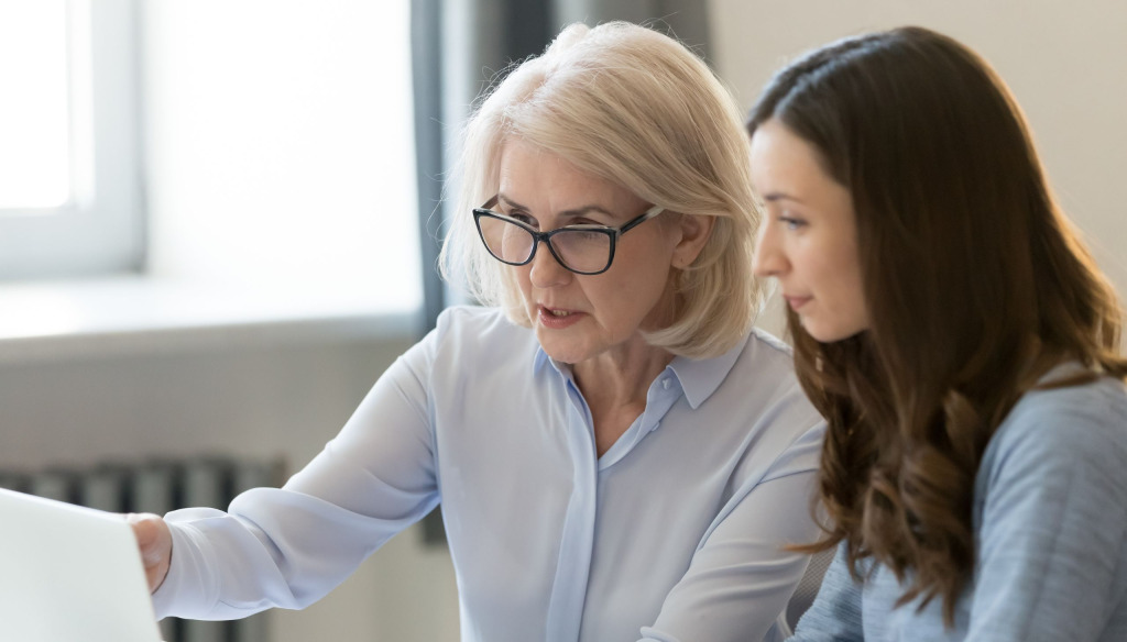 Older woman mentors a younger woman in the office