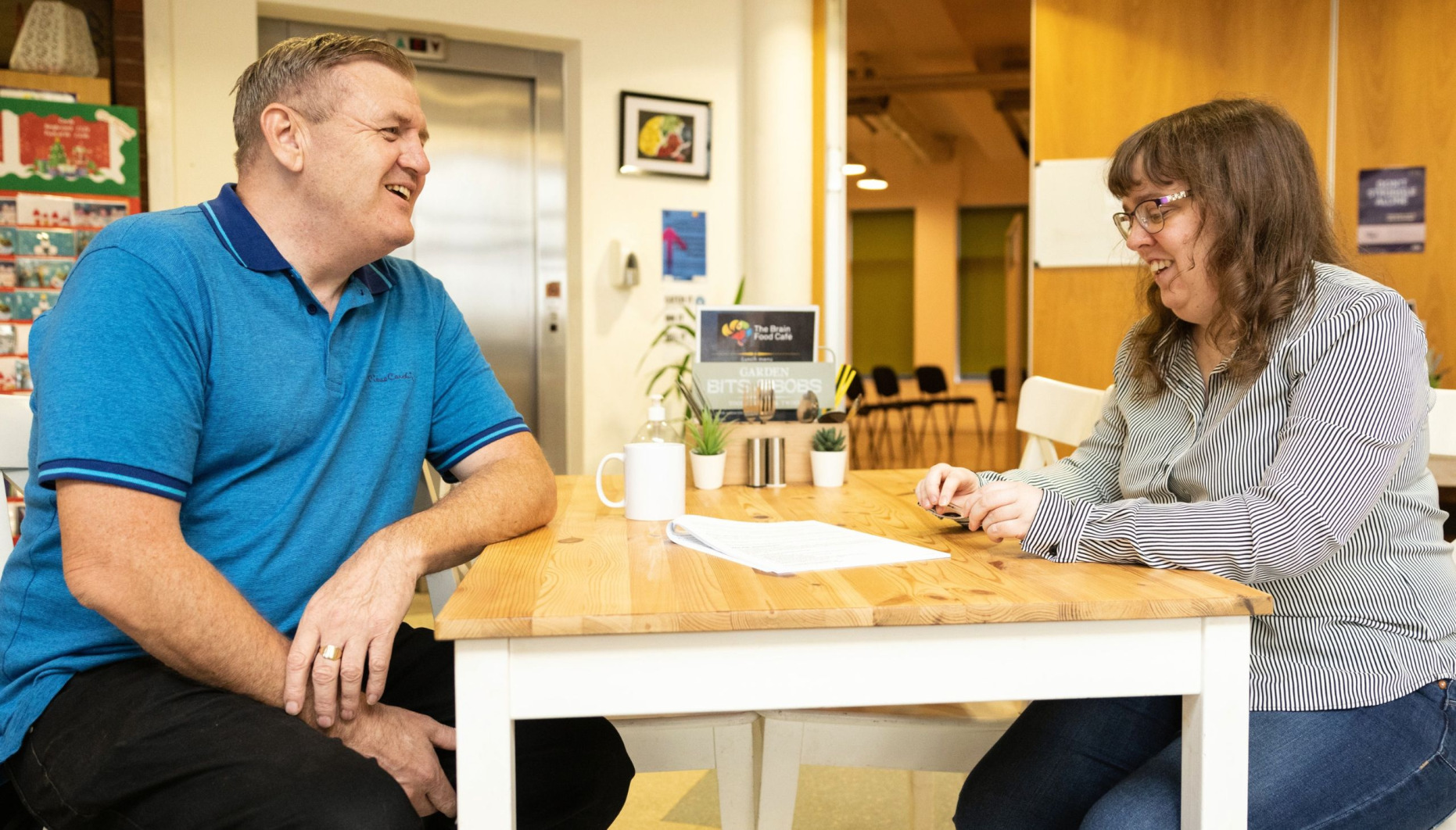 Two people chat in The Brain Charity café