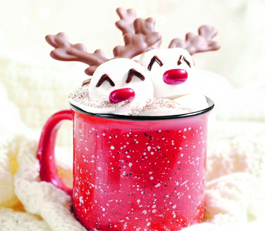 Marshmallows with reindeer faces and horns in a mug of frothy drink