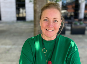 Pippa Sargent, wearing a green top with hair tied back, smiling at camera