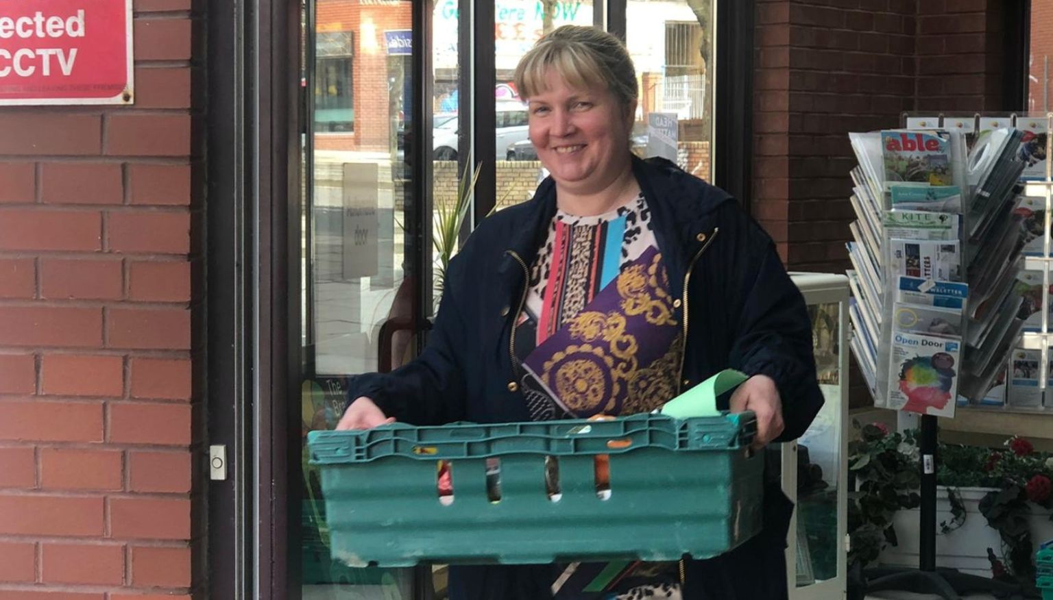 A woman leaving The Brain Charity with a basket of food for delivery during Covid