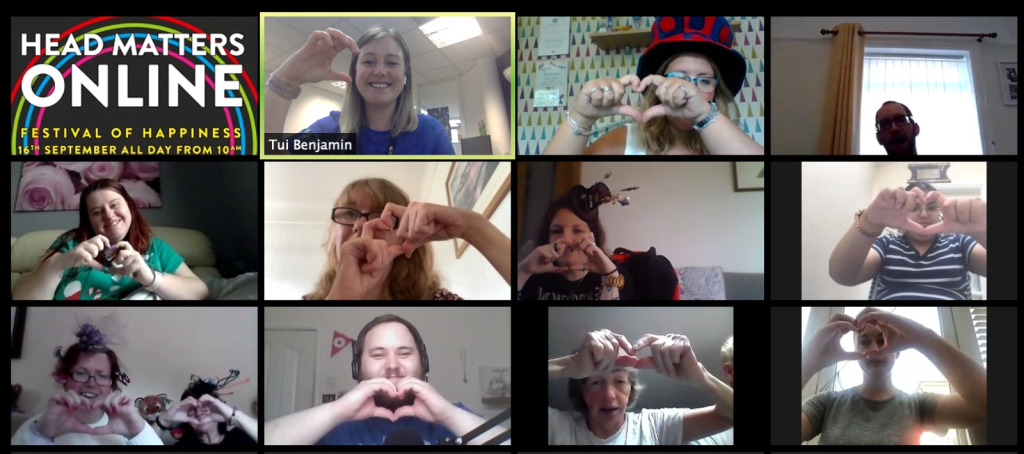 A grid of people on webcams at Head Matters 2020. They are making heart shapes with their hands and smiling