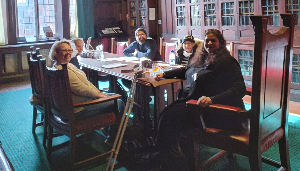 A group of people sitting around a large table in an old library