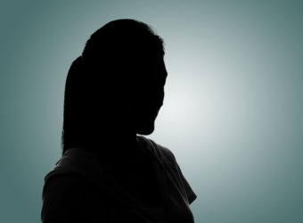 A dark silhouette of a woman against a blue spot lit background