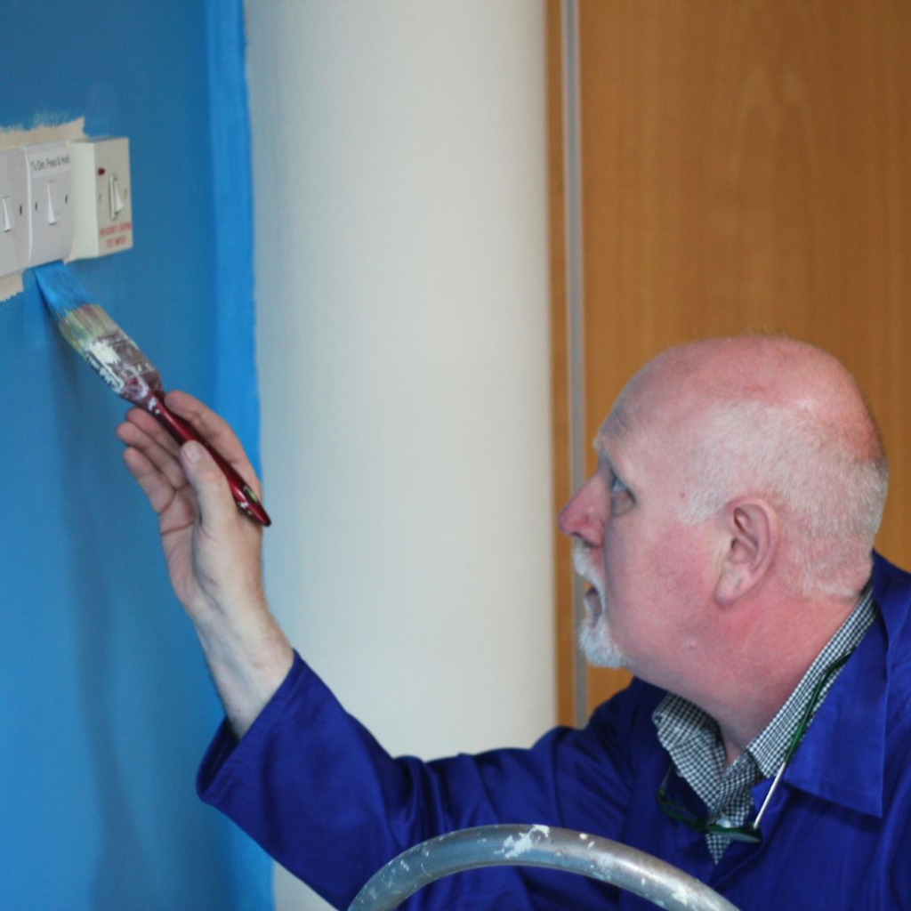 Corporate volunteer painting a wall at The Brain Charity