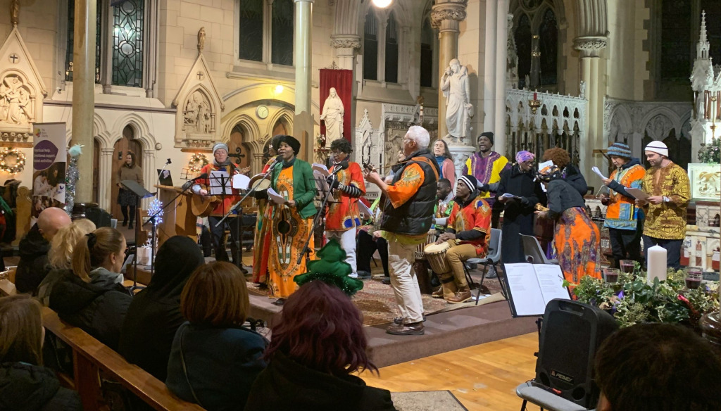 A mixed group of men and women in colourful clothes performing in St Francis Xavier Church, Liverpool