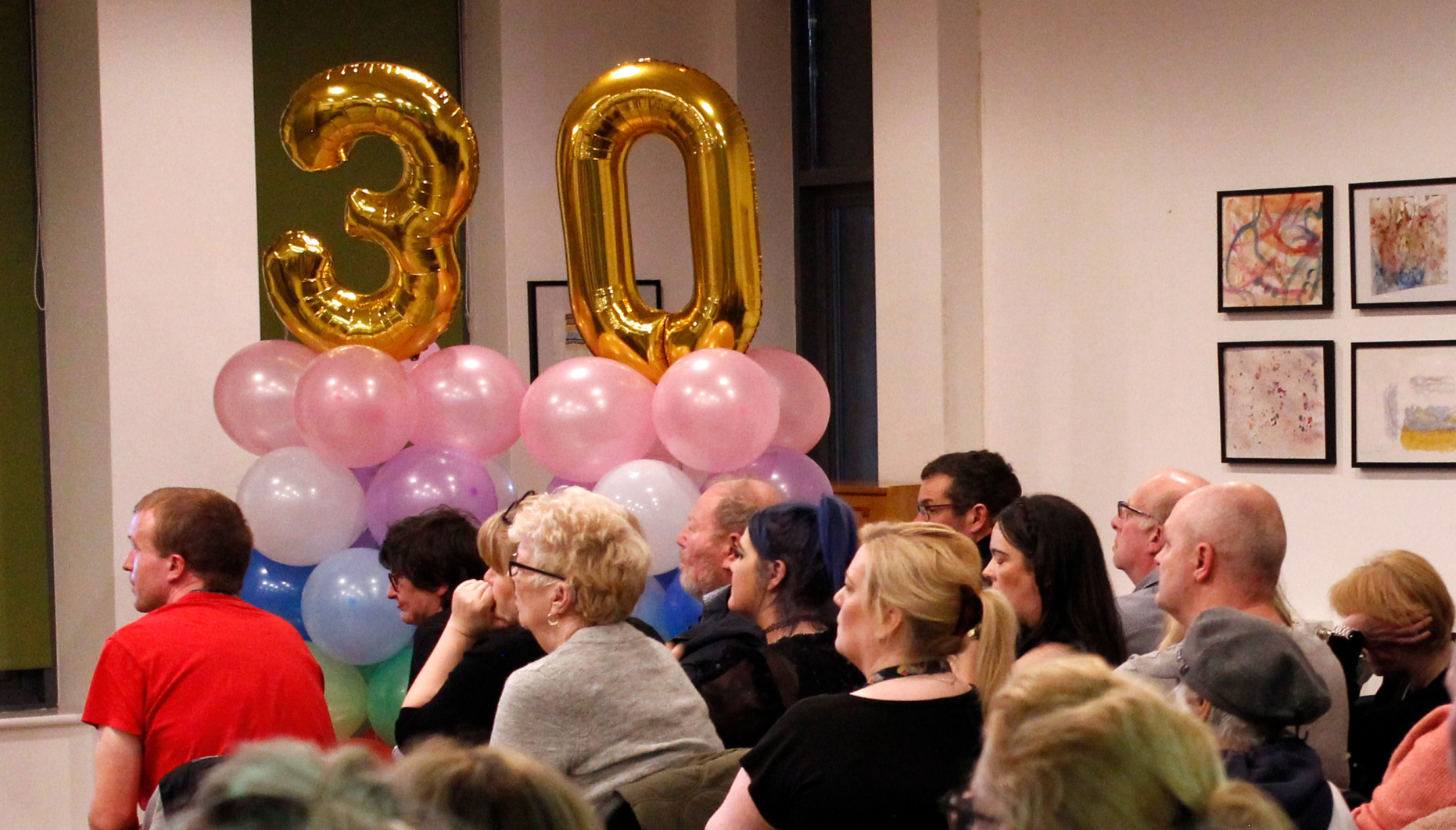 An audience with the number thirty made from baloons behind them