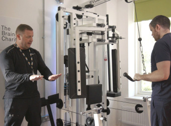 Fitness trainer shows a young man how to use Neuro Gym equipment.