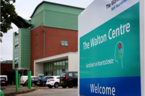 Photo of a hospital from entrance with a sign bearing the words The Walton Centre Welcome