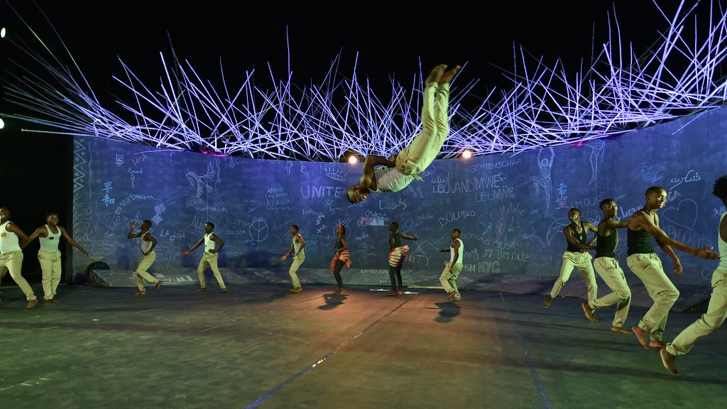 Man doing a back flip in front of a group of dancers