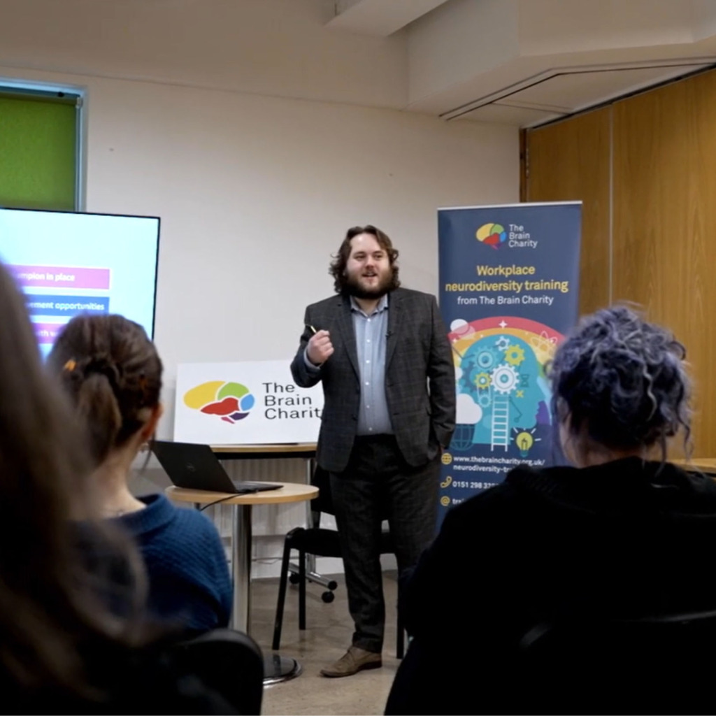 A young man in a suit speaking to an audience of trainees on one of our workplace neurodiversity training courses