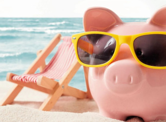 A piggy bank wearing sunglasses on a beach