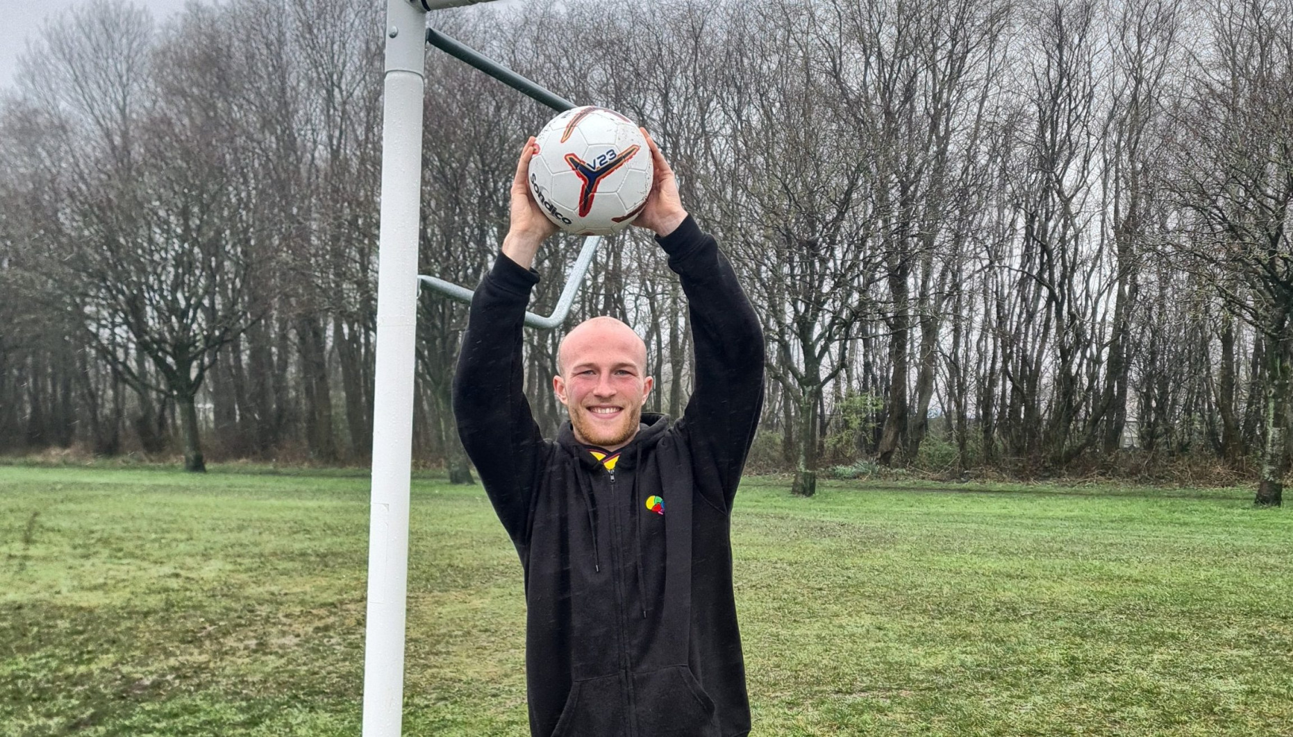 Archie Whitfield, 22, holding a football above his head