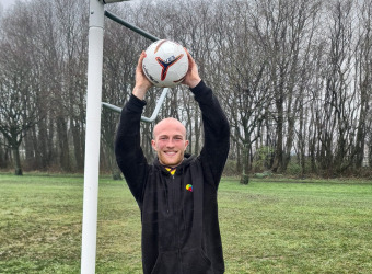 Archie Whitfield, 22, holding a football above his head