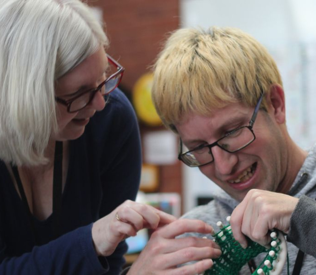 A young man being instructed how to knit