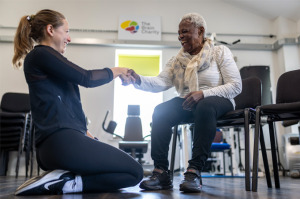 Woman seated and being instructed by a physiotherapist.