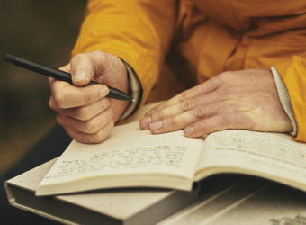 A close up of person's hands writing in a journal