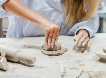 Close up of a woman's hands making a pot from clay