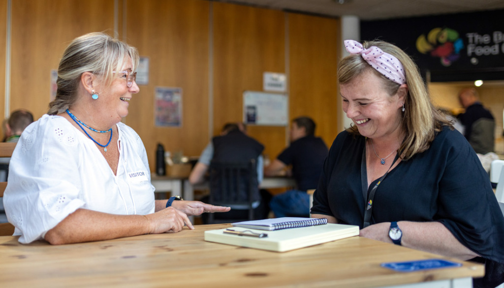 Two women sitting chatting and smiling in The Brain Charity Cafe