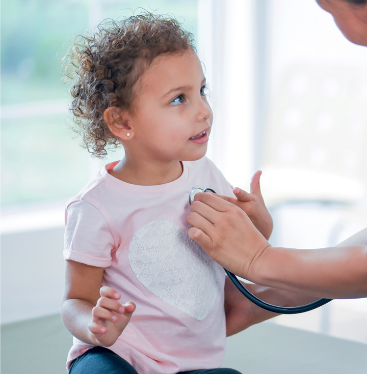 A young child at hospital. They are looking at an adult.