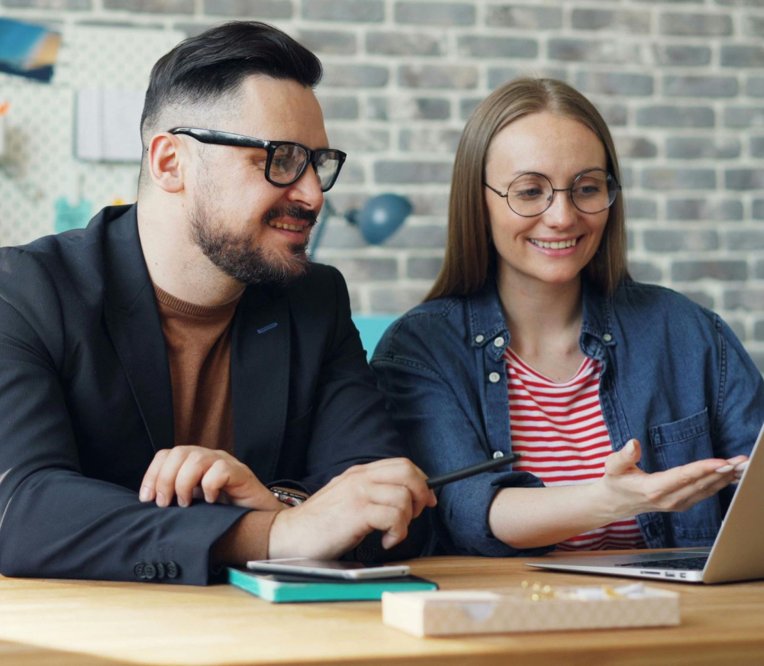 A young couple seated at a table looking at a laptop