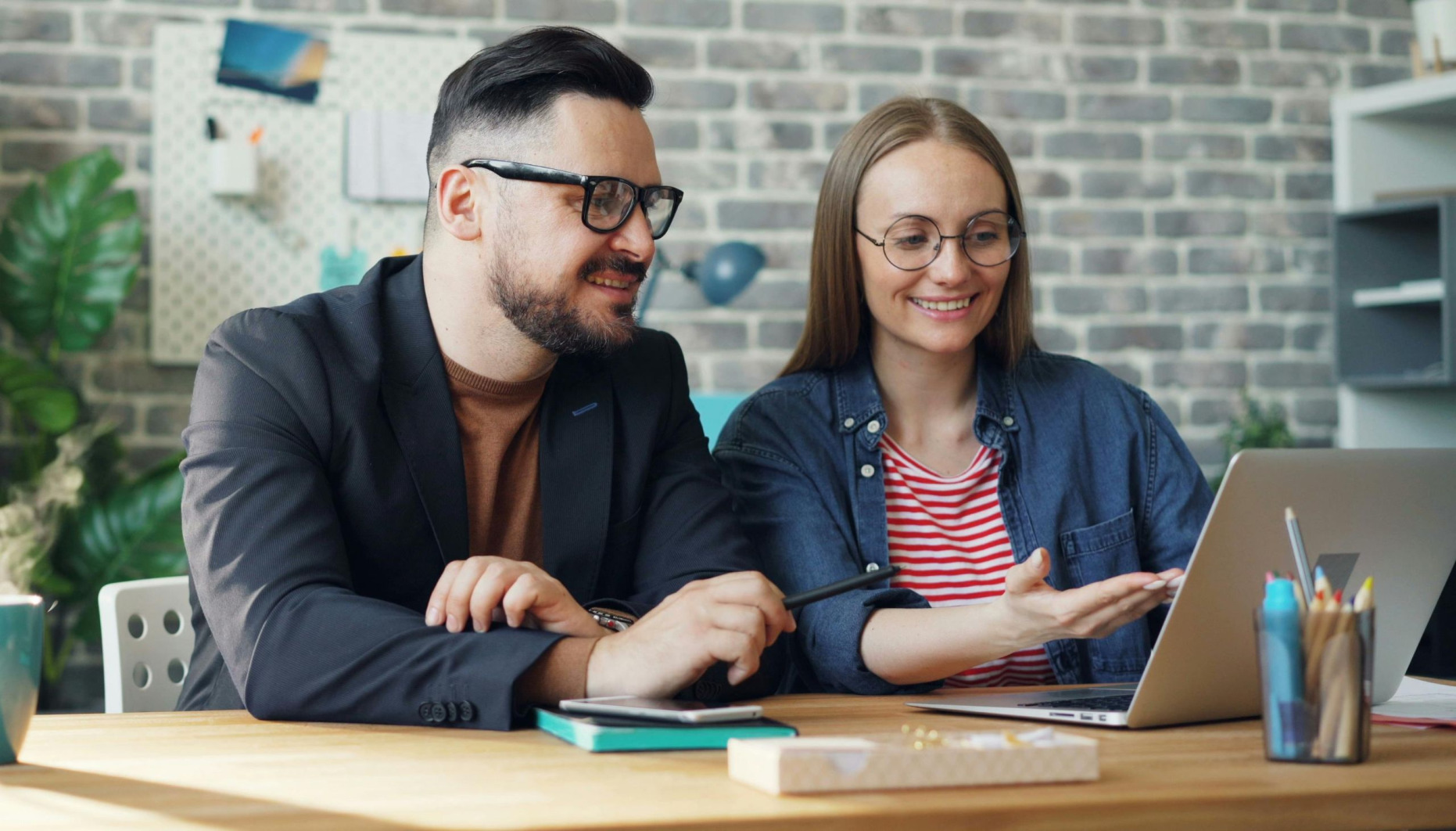 A young couple seated at a table looking at a laptop