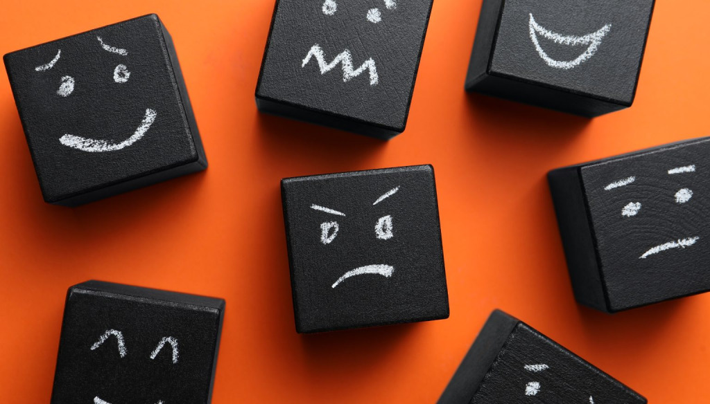 Differing emotion faces drawn in white on black cubes 