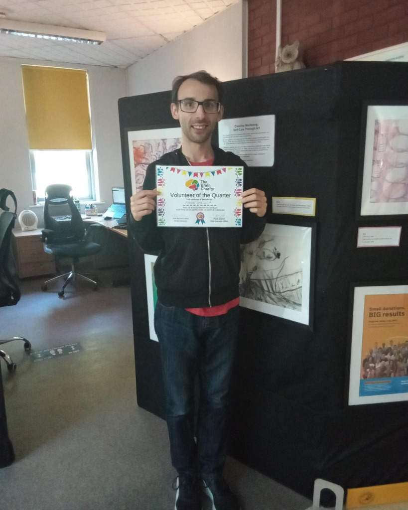 Shawn holding his volunteer of the month certificate