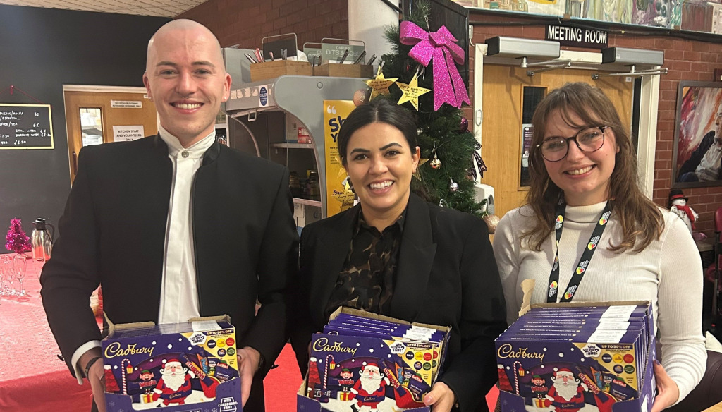 Esme and Adam posing holding donated selection boxes alongside a representative of corporate partner Malmaison