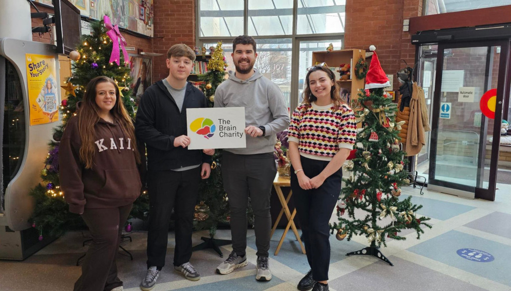 Esme posing with corporate partner volunteers in front of Christmas Trees 