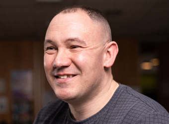 Man with short hair smiling and looking to the left