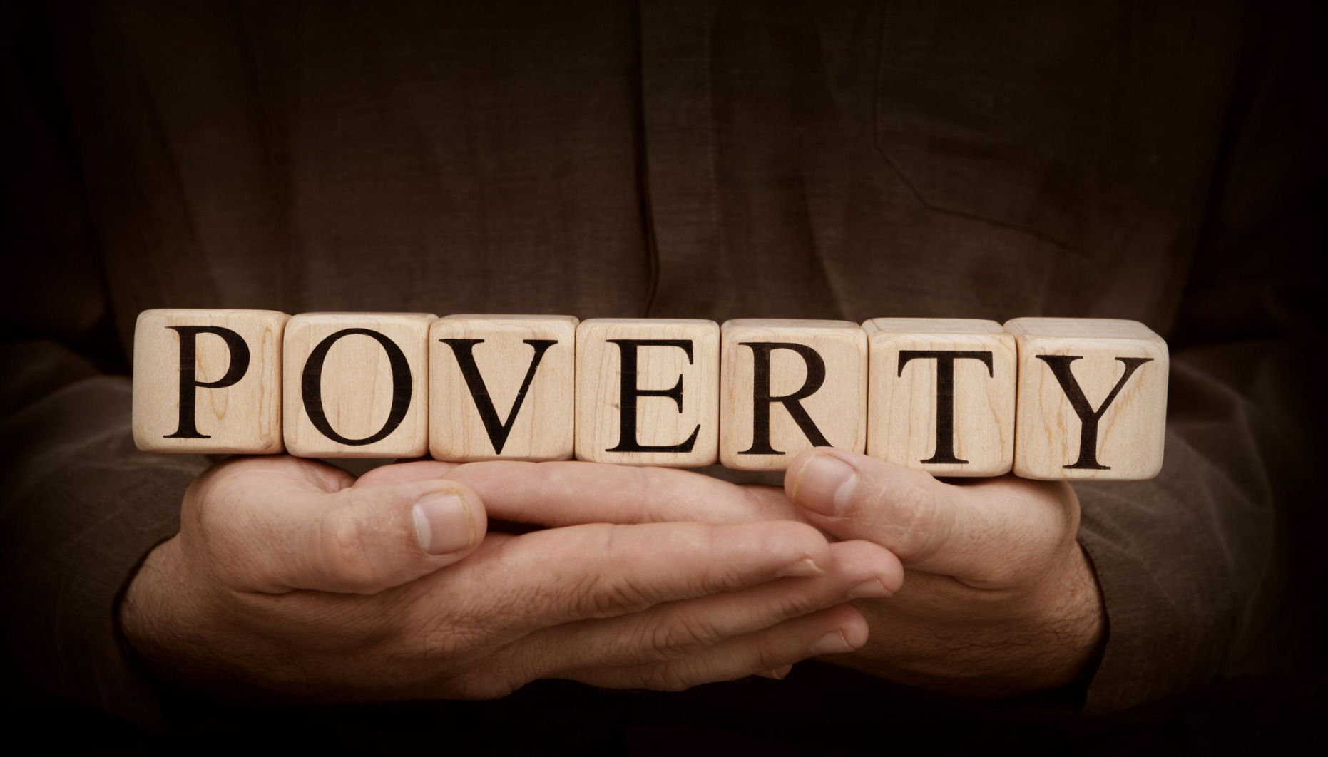 Poverty spelled out on blocks being held in someones hands