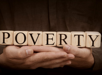 Poverty spelled out on blocks being held in someones hands