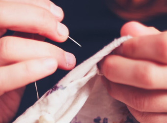 Close up of hands holding a needle and sewing